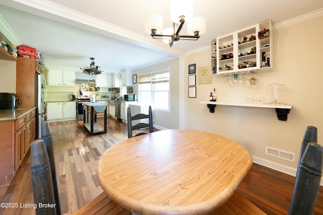 dining room with a chandelier, ornamental molding, wood finished floors, and visible vents