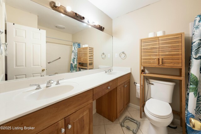 full bathroom featuring toilet, double vanity, a sink, and tile patterned floors