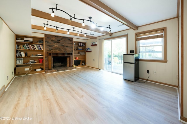 unfurnished living room featuring visible vents, built in features, light wood-style floors, a brick fireplace, and beam ceiling