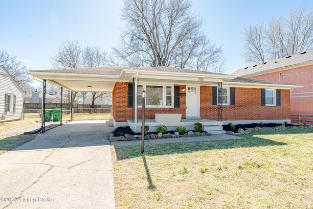 ranch-style home with driveway, fence, a front lawn, a carport, and brick siding