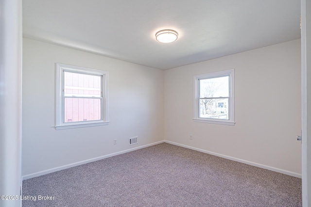 carpeted empty room featuring baseboards and visible vents