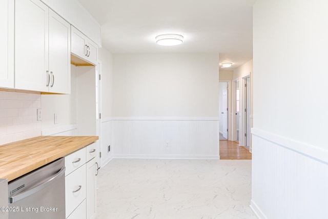 kitchen with marble finish floor, butcher block counters, wainscoting, white cabinetry, and dishwasher