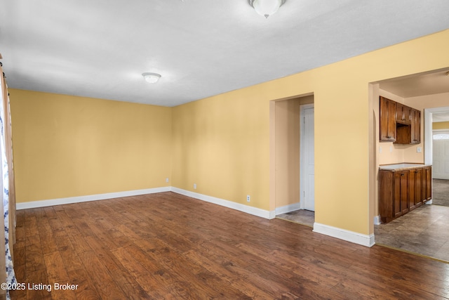 spare room with dark wood-type flooring and baseboards