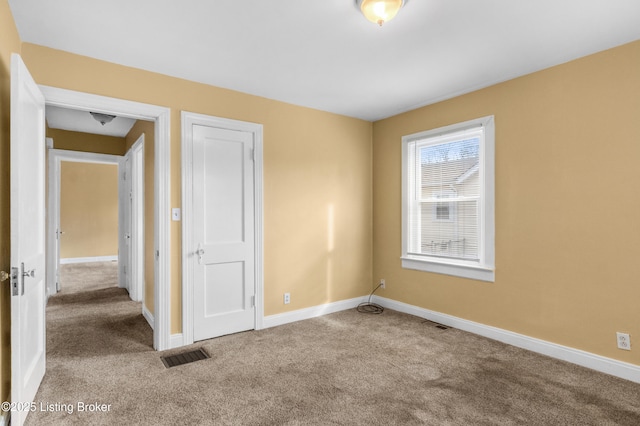 carpeted empty room with visible vents and baseboards