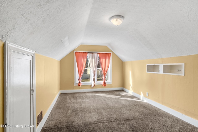 bonus room featuring lofted ceiling, carpet, a textured ceiling, and baseboards