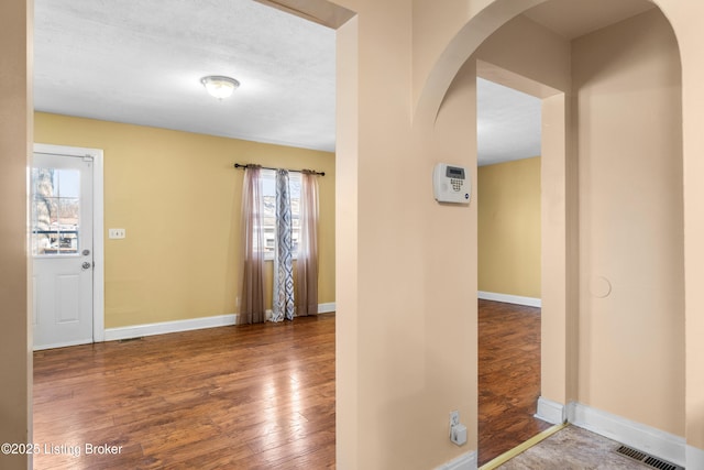 entryway with arched walkways, hardwood / wood-style floors, and plenty of natural light