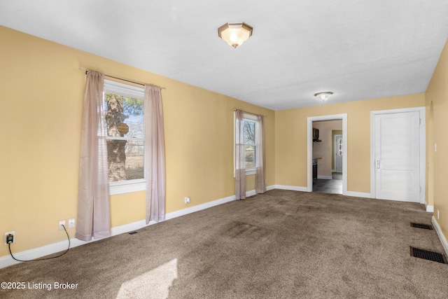 empty room featuring carpet flooring, visible vents, and baseboards