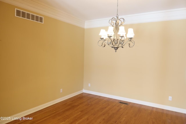 spare room with ornamental molding, visible vents, an inviting chandelier, and wood finished floors