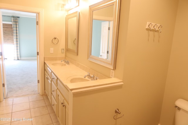 bathroom with toilet, double vanity, a sink, and tile patterned floors