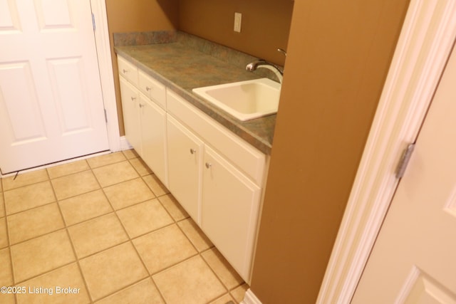 kitchen with light tile patterned floors, a sink, and white cabinetry