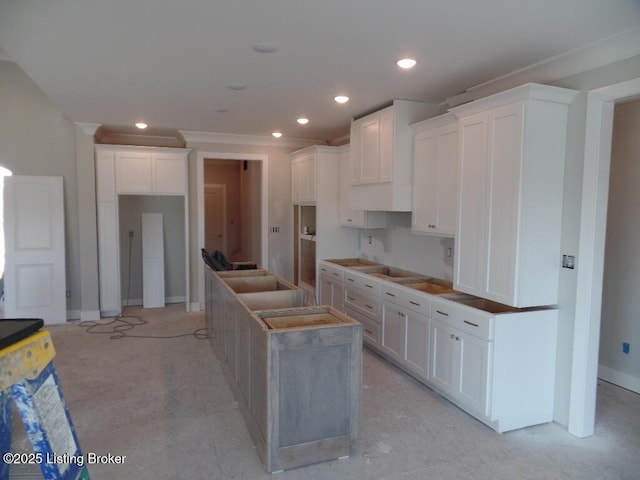 kitchen with recessed lighting, white cabinetry, a kitchen island, and baseboards