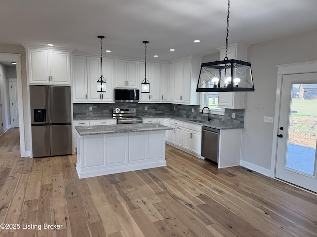 kitchen with stainless steel appliances, light wood-style floors, white cabinets, and a sink