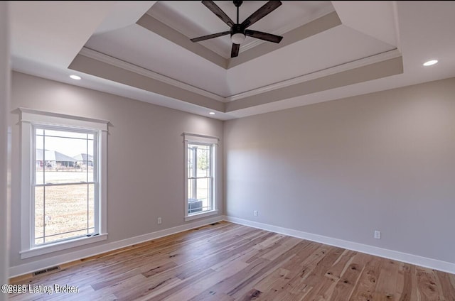 unfurnished room featuring light wood finished floors, baseboards, a tray ceiling, and recessed lighting