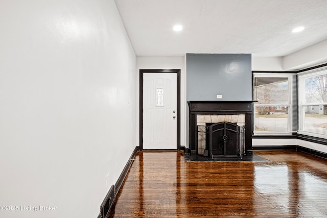 unfurnished living room featuring a fireplace, wood finished floors, visible vents, and baseboards