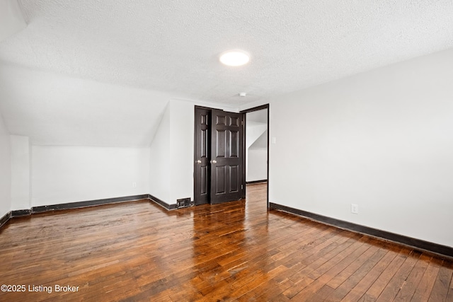 bonus room with a textured ceiling, baseboards, and hardwood / wood-style floors