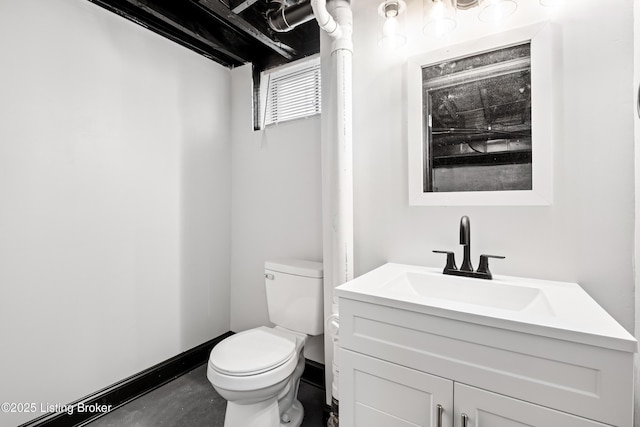 bathroom with toilet, concrete floors, baseboards, and vanity