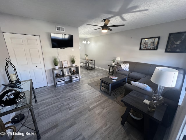 living area with baseboards, visible vents, a ceiling fan, wood finished floors, and a textured ceiling