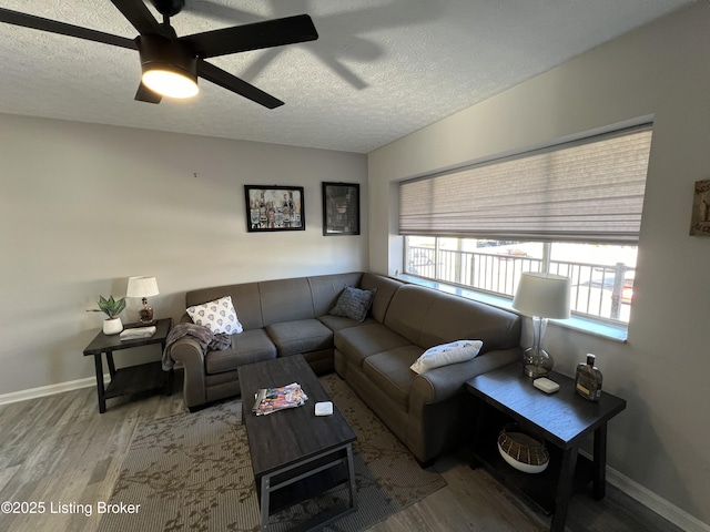 living room with a ceiling fan, a textured ceiling, baseboards, and wood finished floors