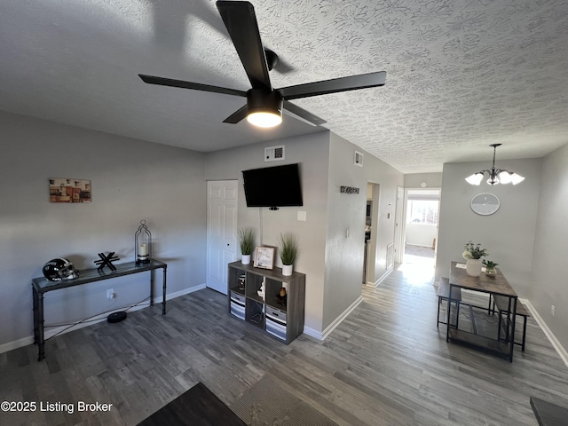 interior space with visible vents, a textured ceiling, baseboards, and wood finished floors