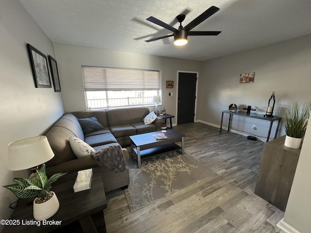 living area featuring ceiling fan, a textured ceiling, baseboards, and wood finished floors