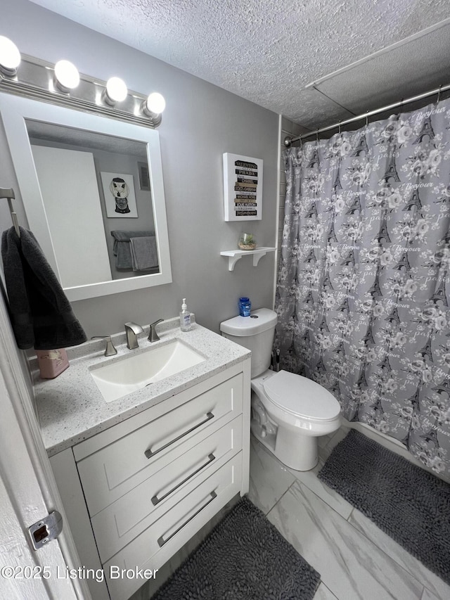 full bath with marble finish floor, curtained shower, toilet, vanity, and a textured ceiling