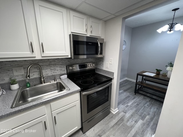 kitchen featuring a notable chandelier, appliances with stainless steel finishes, a sink, and white cabinets