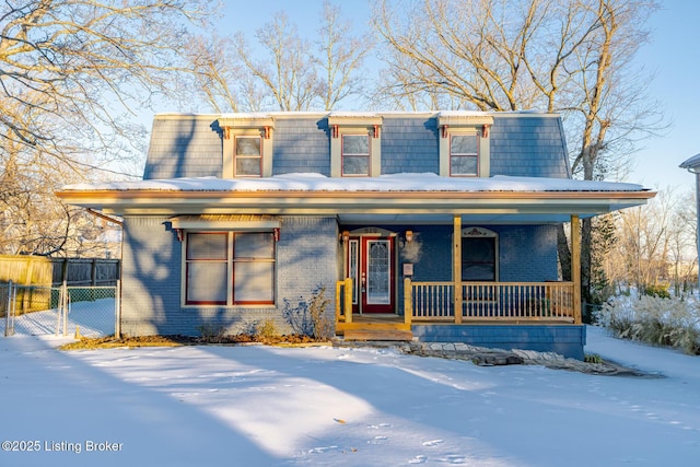 victorian home featuring brick siding, mansard roof, a porch, and fence