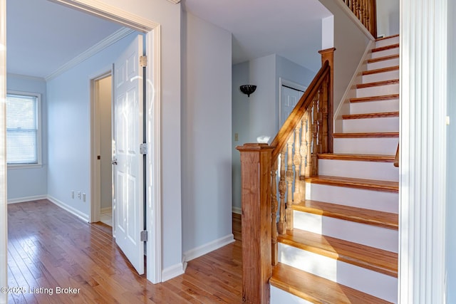 staircase featuring ornamental molding, wood-type flooring, and baseboards