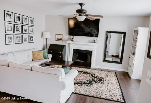 living area with ceiling fan, a fireplace, baseboards, and wood finished floors