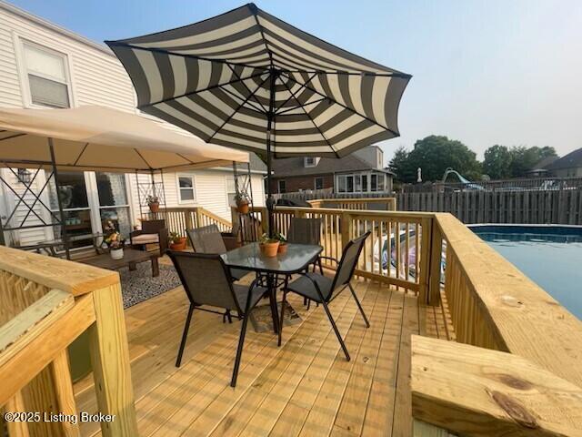 wooden deck with a fenced in pool, outdoor dining space, and fence