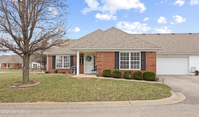 ranch-style home featuring a front yard, brick siding, driveway, and roof with shingles