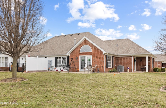 view of front facade featuring french doors, brick siding, a front lawn, and fence