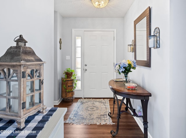 entrance foyer with a textured ceiling, baseboards, and wood finished floors