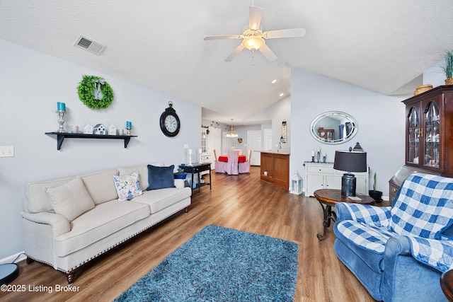 living area with visible vents, ceiling fan, vaulted ceiling, a textured ceiling, and wood finished floors