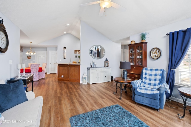 living area featuring lofted ceiling, baseboards, wood finished floors, and ceiling fan with notable chandelier