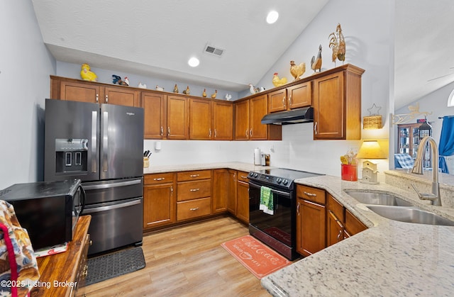 kitchen with lofted ceiling, under cabinet range hood, a sink, black appliances, and brown cabinetry