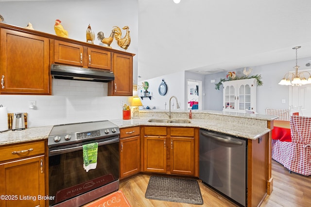 kitchen with under cabinet range hood, a peninsula, a sink, appliances with stainless steel finishes, and brown cabinets