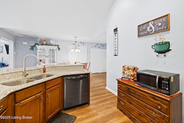 kitchen featuring light wood-style flooring, light stone counters, appliances with stainless steel finishes, brown cabinets, and a sink