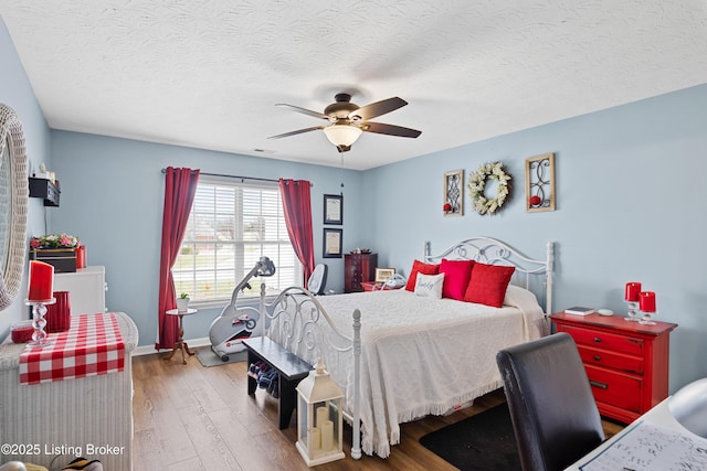 bedroom with a textured ceiling, wood finished floors, visible vents, a ceiling fan, and baseboards