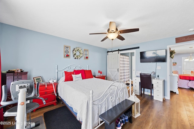 bedroom with a barn door, a ceiling fan, and wood finished floors