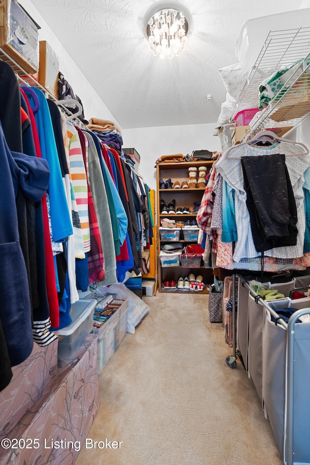 spacious closet with carpet floors and an inviting chandelier