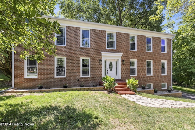 view of front facade with brick siding and a front yard