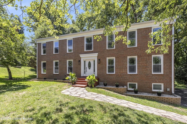 colonial inspired home featuring a front yard and brick siding