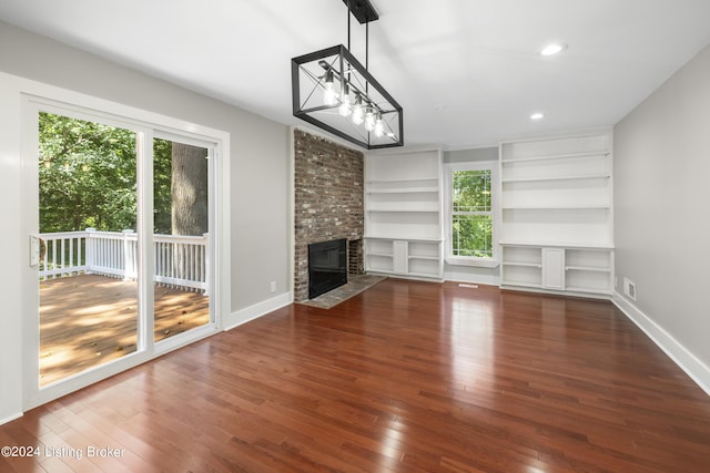 unfurnished living room with visible vents, baseboards, wood-type flooring, a brick fireplace, and recessed lighting