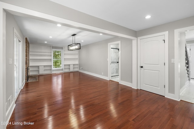 unfurnished living room with a chandelier, hardwood / wood-style flooring, recessed lighting, baseboards, and built in features