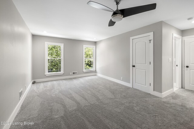 carpeted spare room with baseboards, visible vents, and ceiling fan