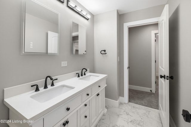 bathroom featuring marble finish floor, double vanity, a sink, and baseboards