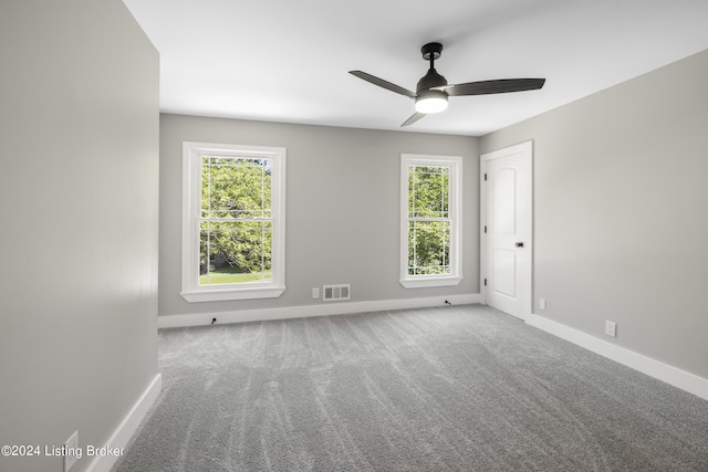 spare room featuring carpet floors, visible vents, and baseboards