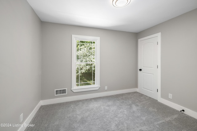 unfurnished room with carpet floors, visible vents, and baseboards