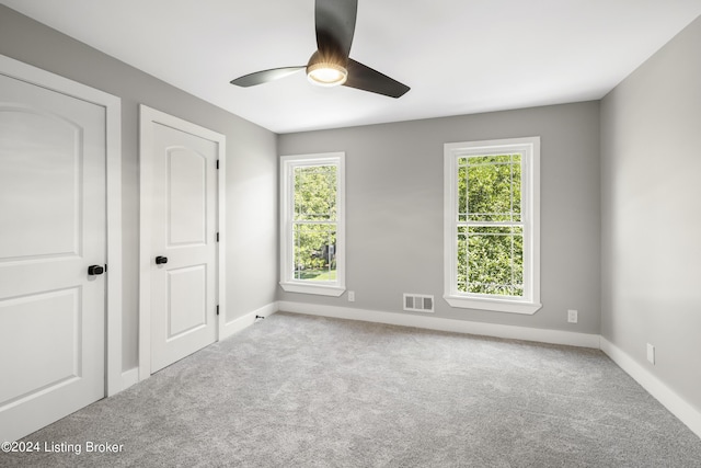 unfurnished room featuring carpet floors, baseboards, visible vents, and a wealth of natural light